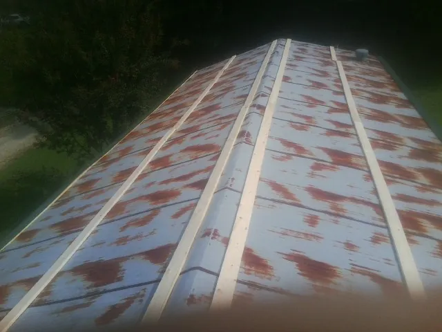 Rusted metal roof panels with new wood purlins before replacement in Lake Lynn