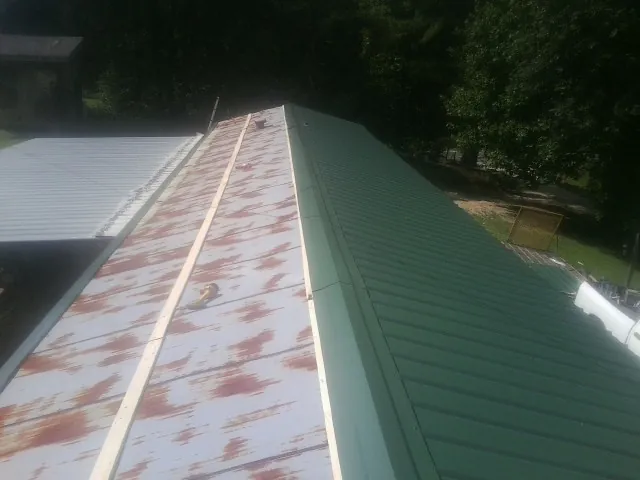 Old rusted panels beside newly installed green metal roofing — Wind Damage Roof Repair by Roofing Brothers in Lake Lynn