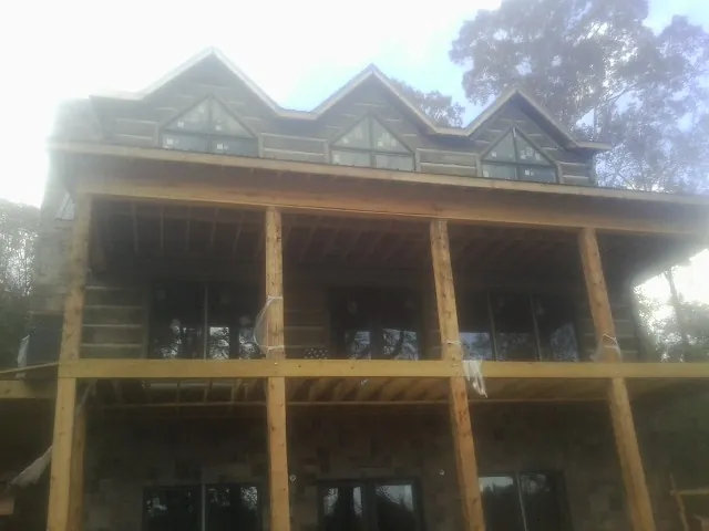 Dormers and porch framing on a large log home under construction — Roof Coating work by our crew in Lake Lynn