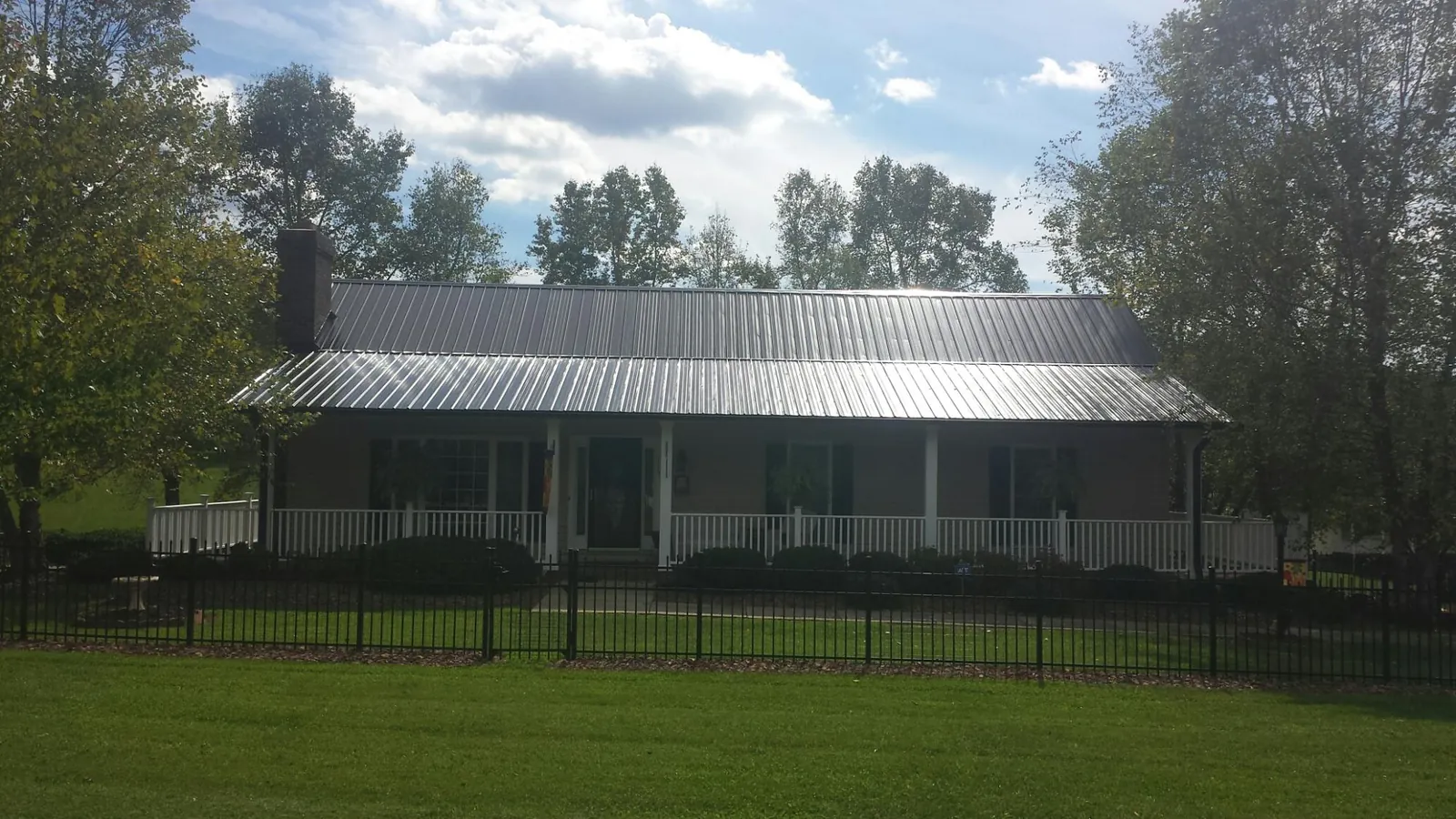 Gray metal roof on a brick ranch with a full width front porch — Gutter Guard Installation work by our crew in Lake Lynn