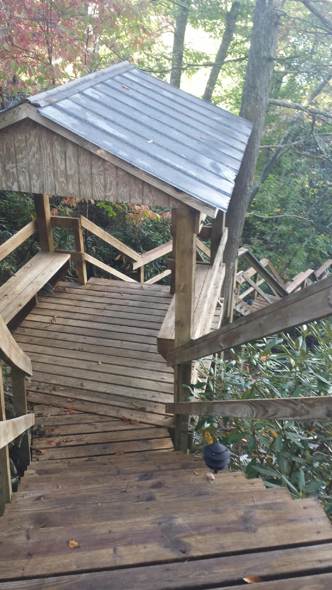 Metal roofed shelter over wooden steps on a wooded walkway — Skylight Repair & Installation work by our crew in Lake Lynn