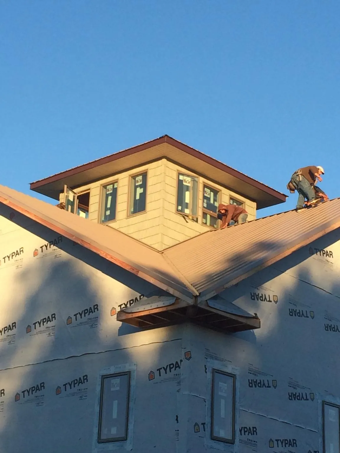 Roofers working around a rooftop cupola on a new metal roof at sunset — Roof Waterproofing in Lake Lynn by Roofing Brothers